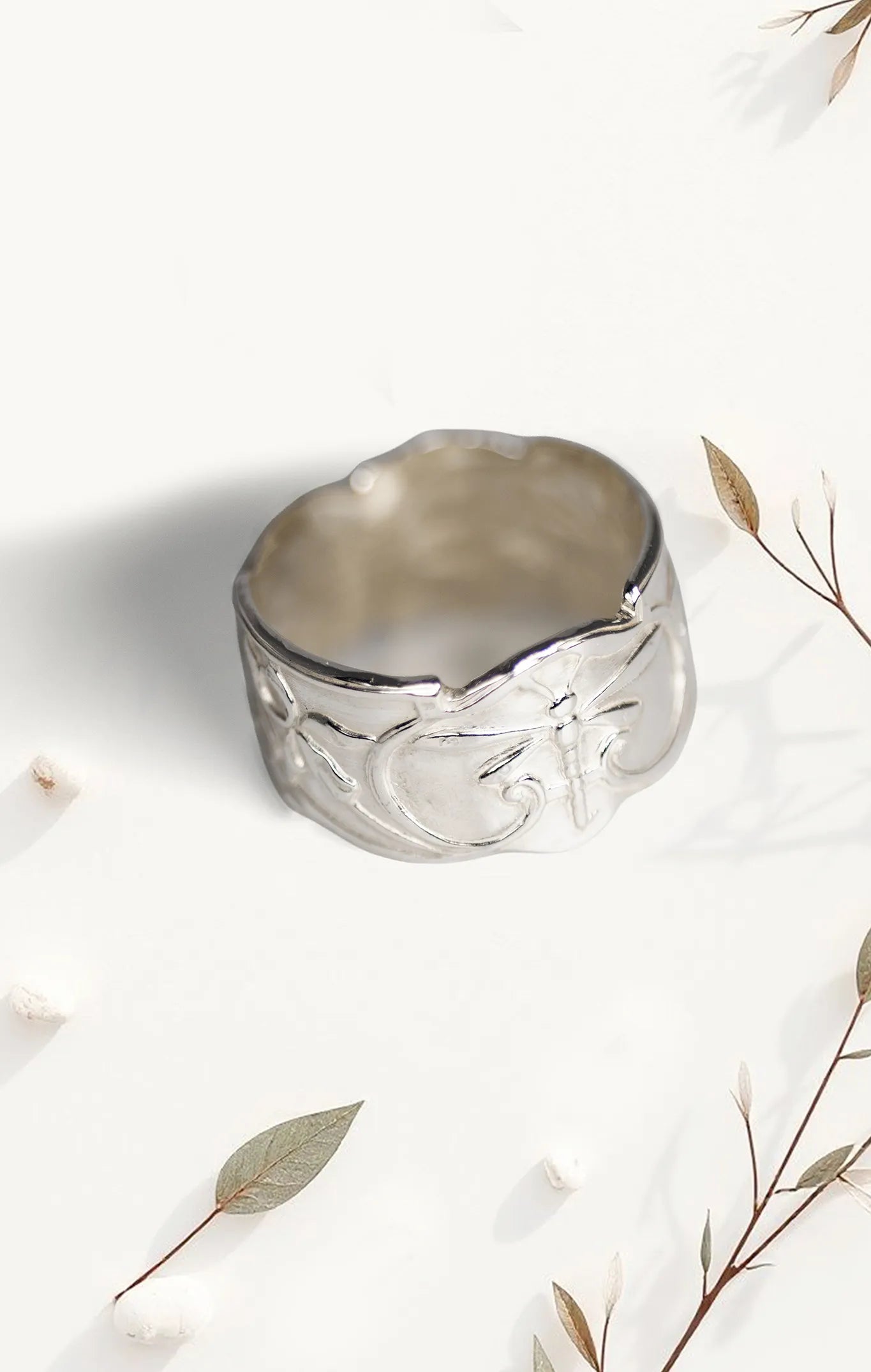 Silver ring with intricate design on a light background