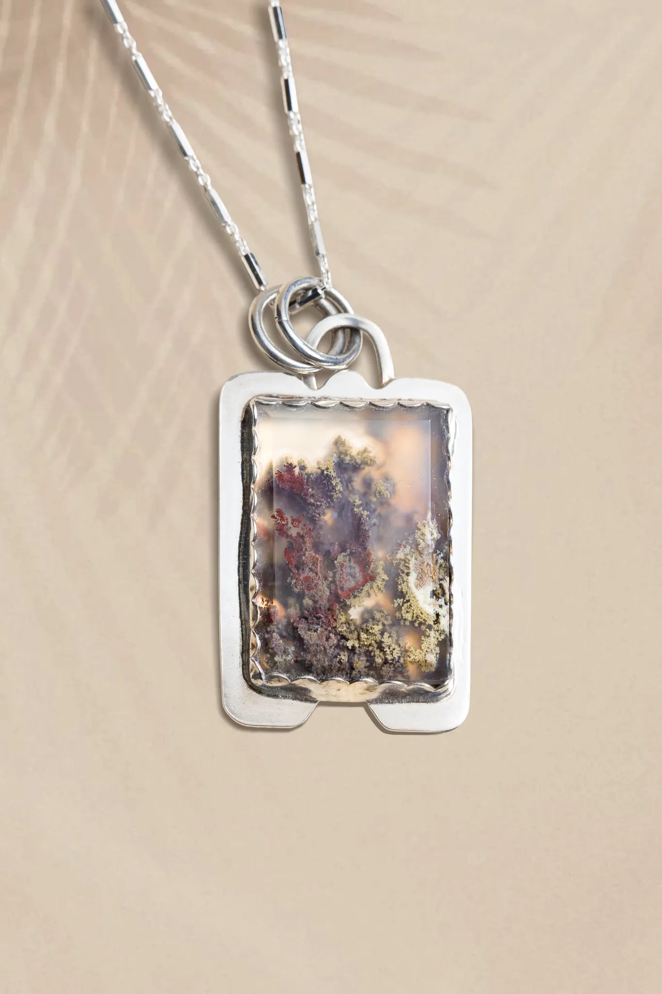 Necklace with a rectangular pendant on a beige background