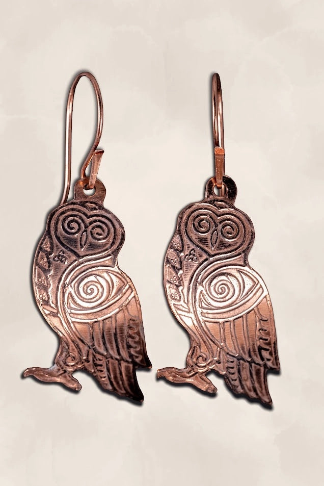 Copper owl-shaped earrings on a light background