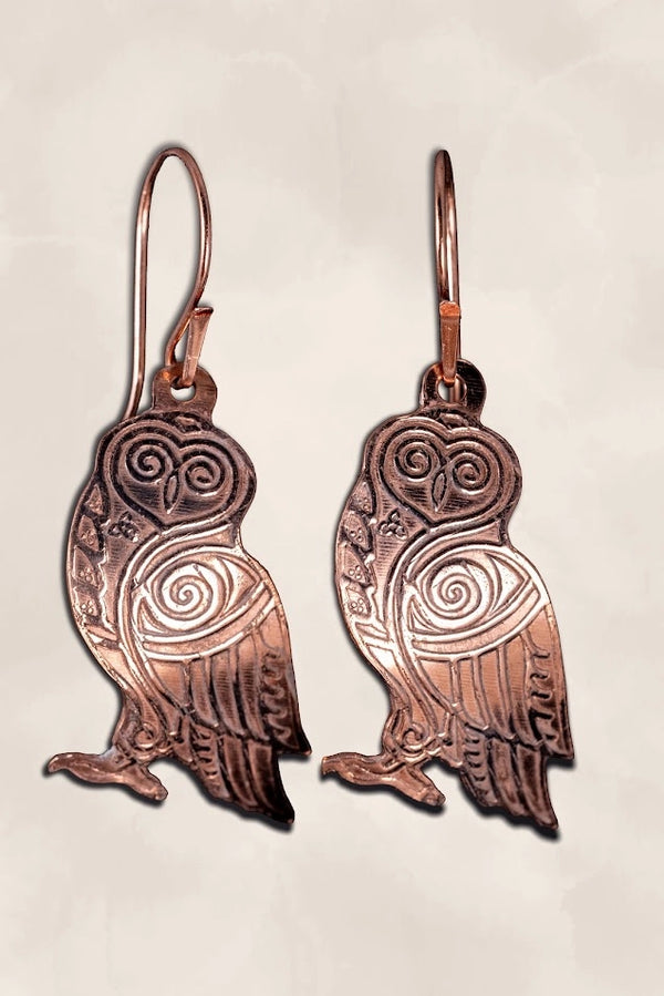 Copper owl-shaped earrings on a light background