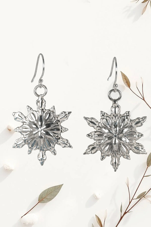 Silver snowflake earrings on a white background with floral elements