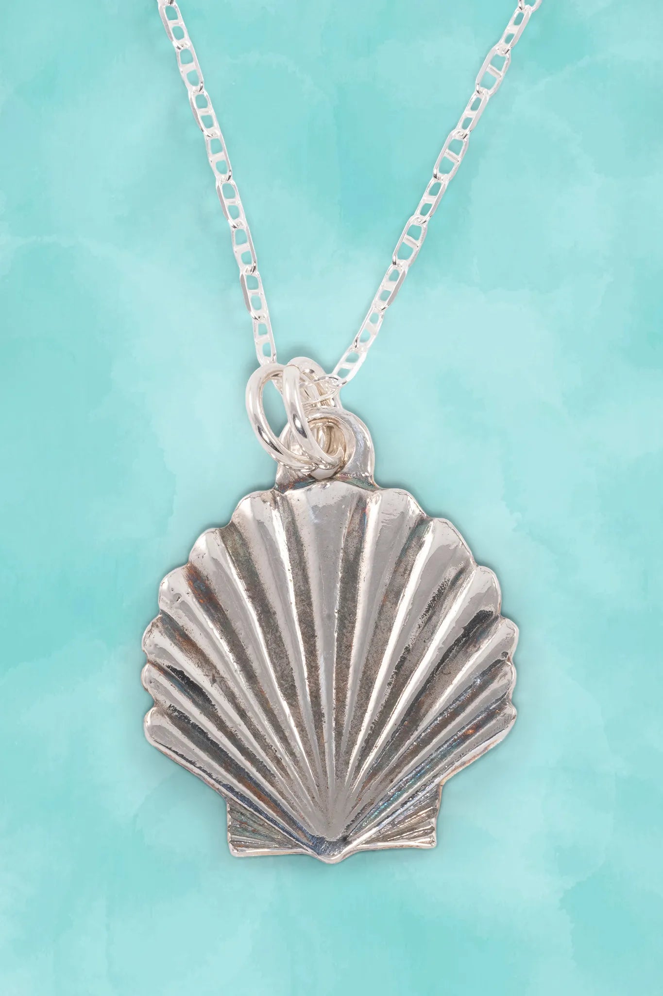 Silver shell pendant necklace on a turquoise background
