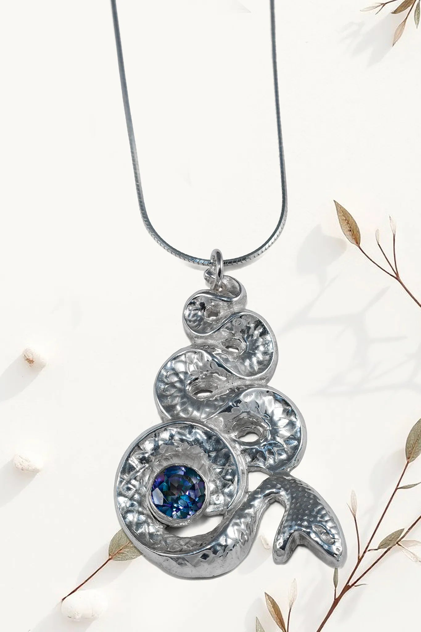 Silver pendant with blue gemstone on a white background