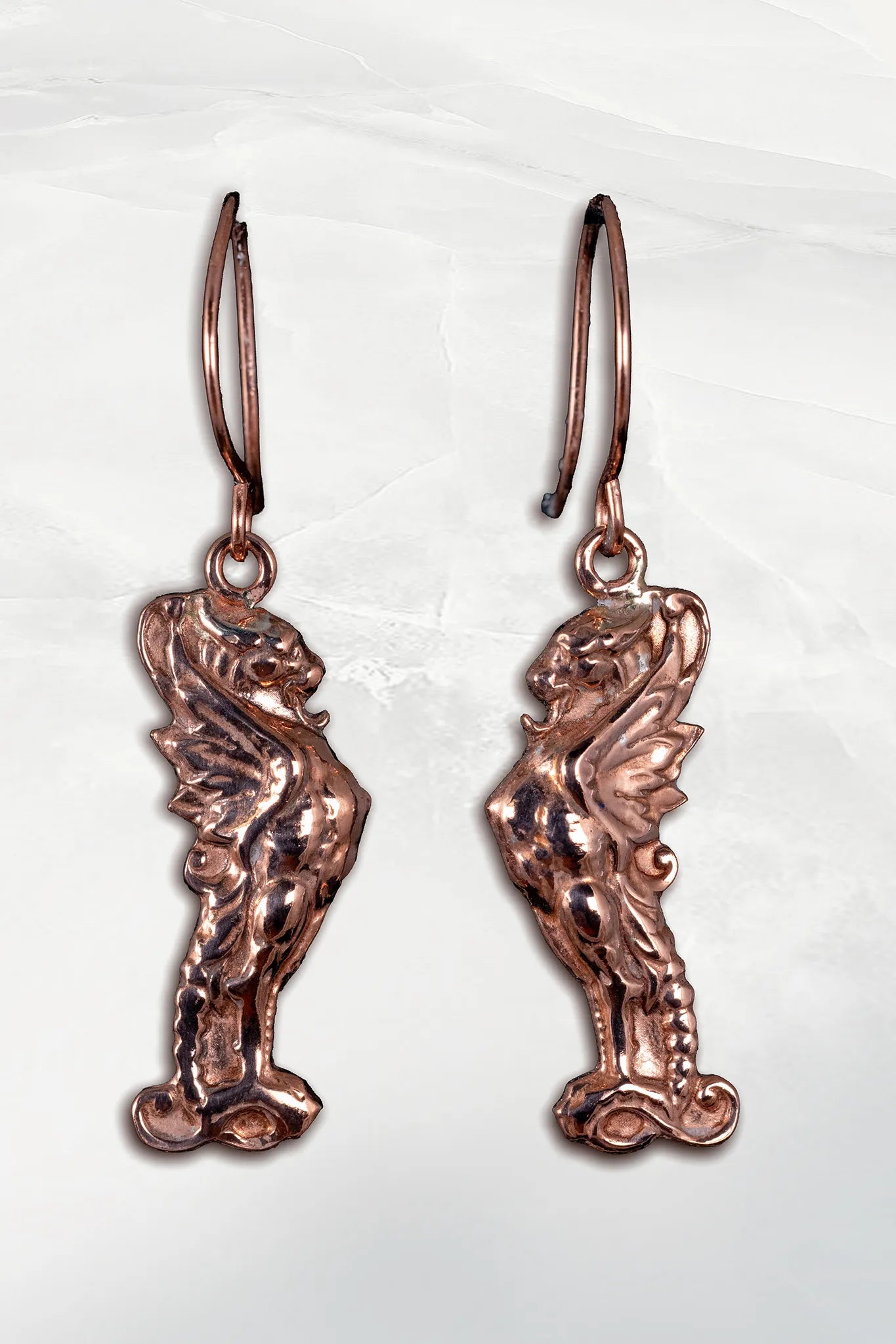 Pair of copper fairy wing earrings on a white background