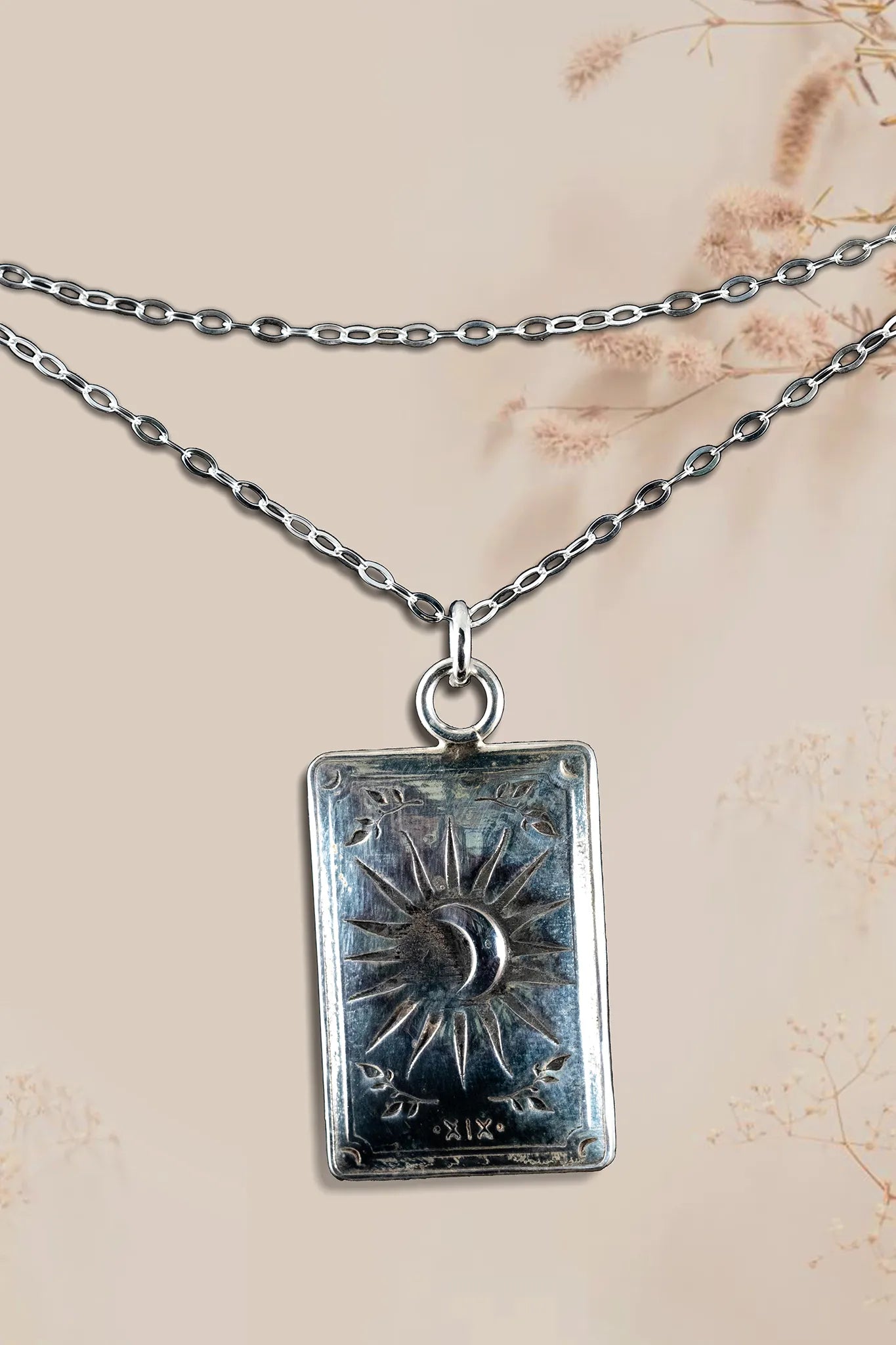 Silver tarot card pendant necklace on a beige background