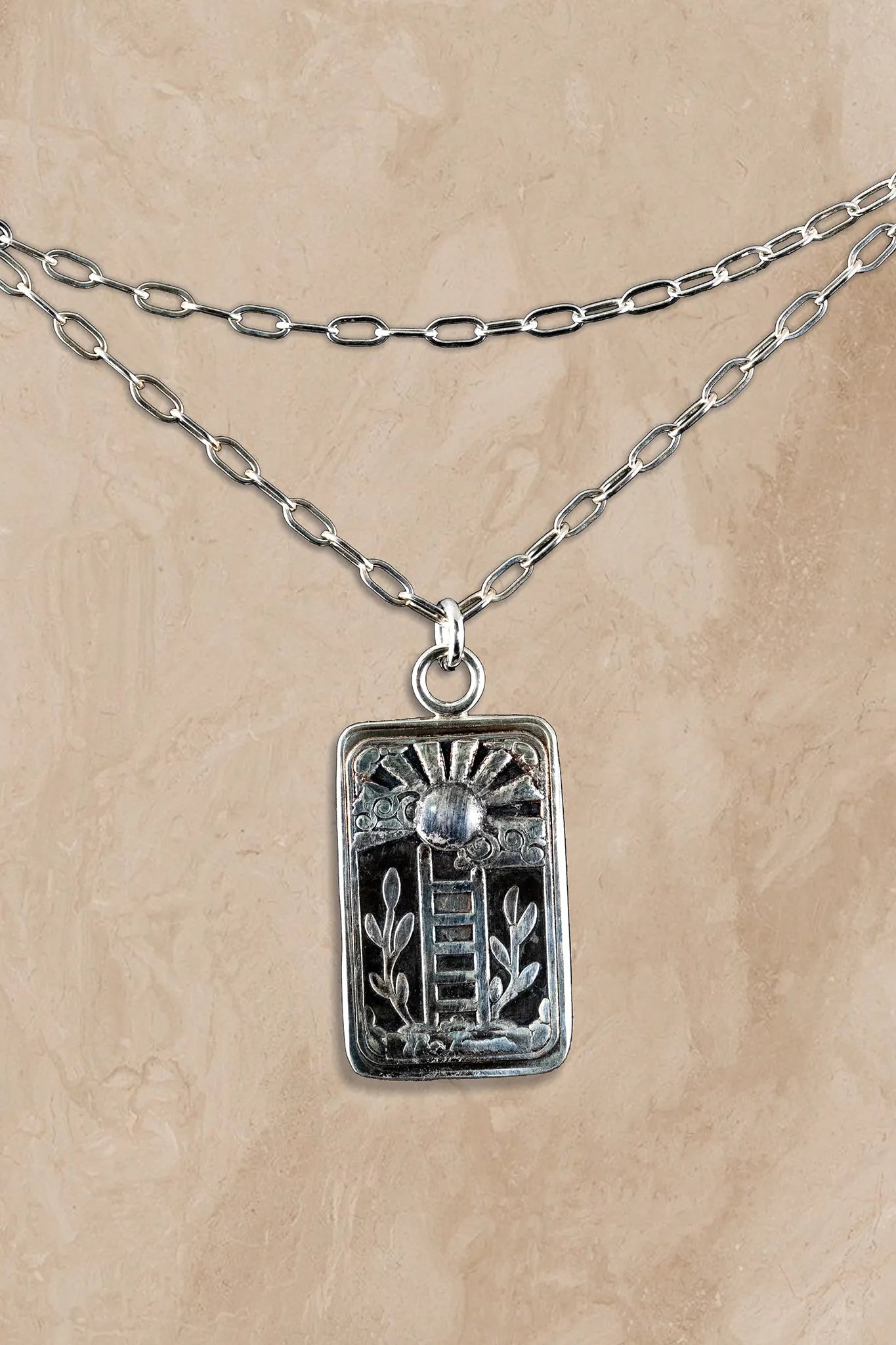 Silver necklace with a rectangular pendant on a beige background