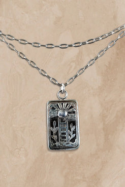 Silver necklace with a rectangular pendant on a beige background