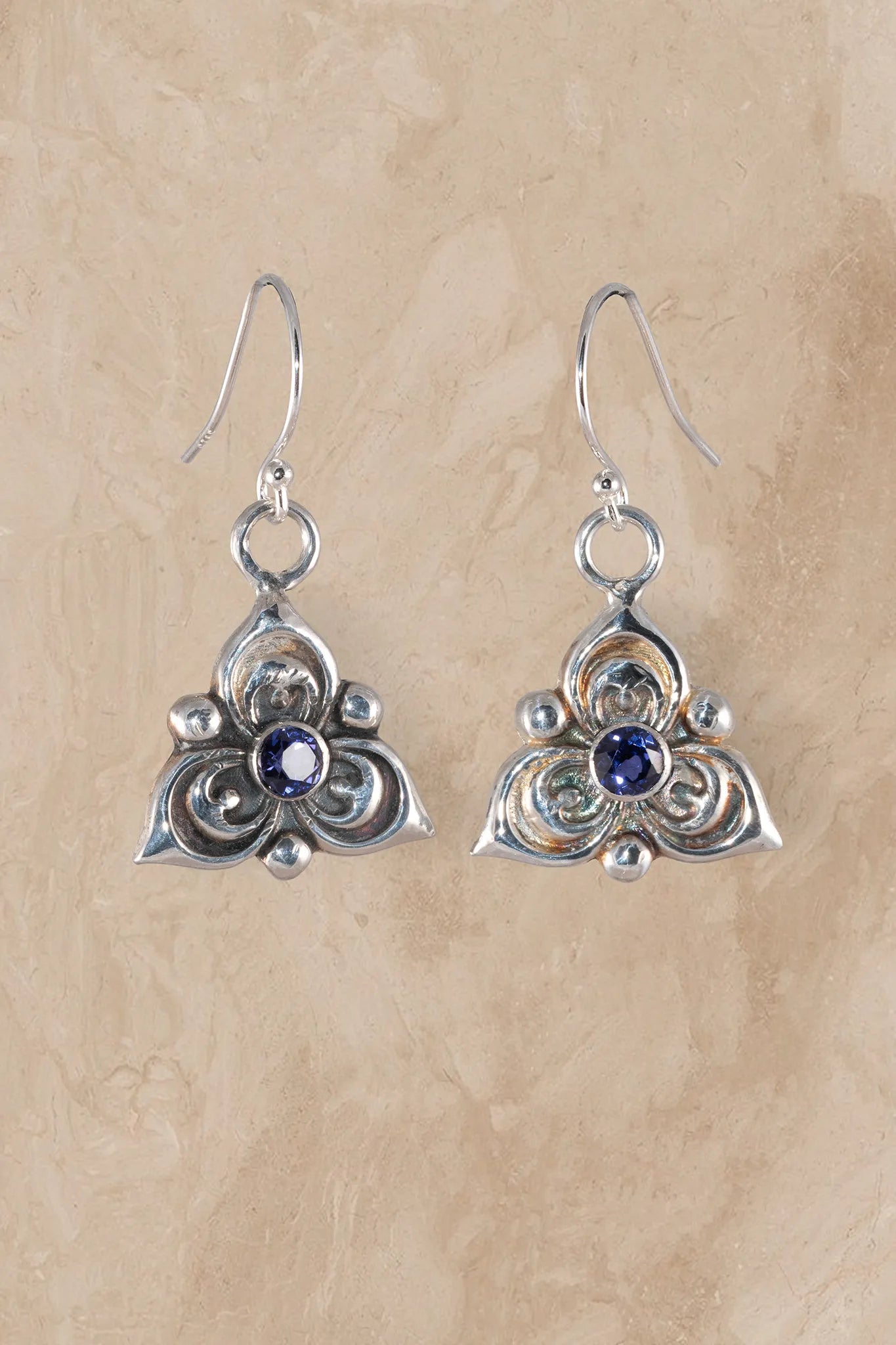 Silver earrings with blue gemstones on a beige background