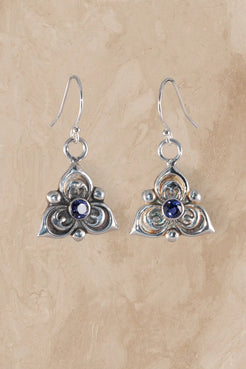 Silver earrings with blue gemstones on a beige background
